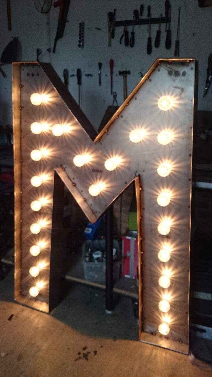 The giant M lit in the workshop